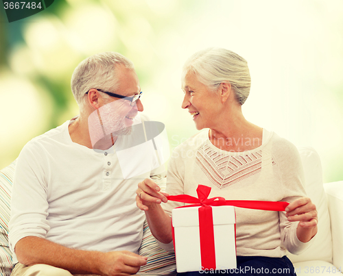 Image of happy senior couple with gift box at home