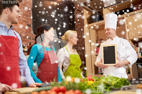 Image of happy friends and chef cook with menu in kitchen
