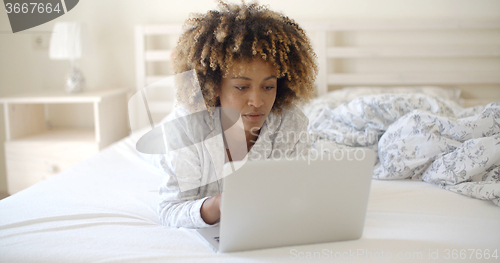 Image of Woman Looking At Laptop In Bed At Home