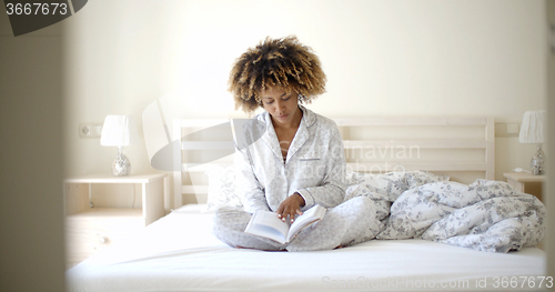 Image of Woman Reading A Book On Bed