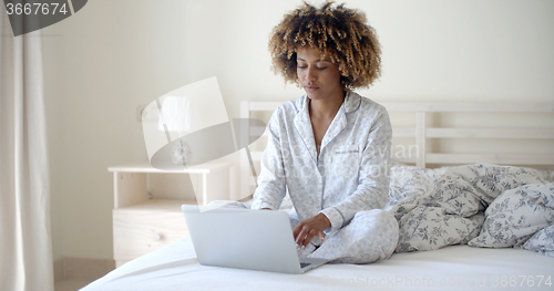 Image of Young Woman Using Laptop On Bed
