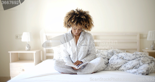 Image of Woman Reading A Book On Bed