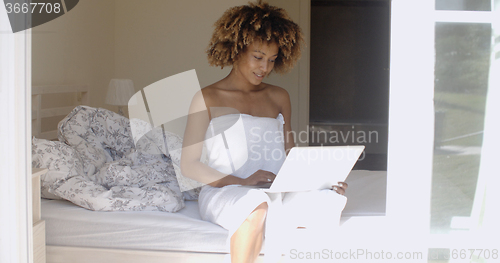 Image of Young Woman Using Laptop On Bed