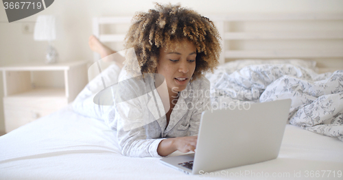 Image of Woman Looking At Laptop In Bed At Home