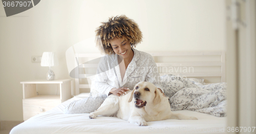 Image of Woman Is Holding A Dog On A Bed