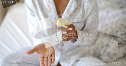 Image of Woman Taking Pills On The Bed.