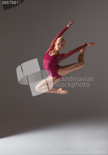 Image of Young beautiful modern style dancer jumping on a studio background