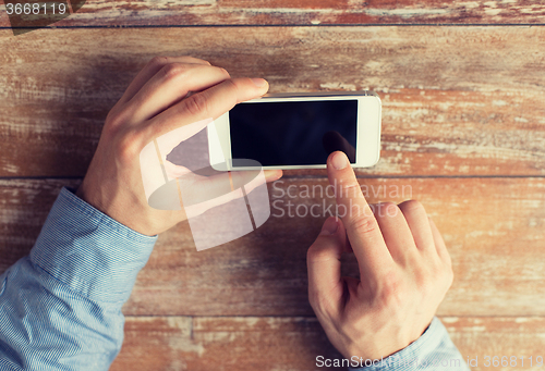 Image of close up of male hands with smartphone on table