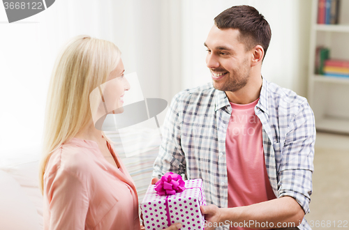 Image of happy man giving woman gift box at home