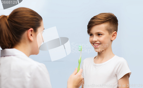 Image of doctor with toothbrush and happy boy in clinic