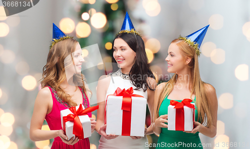 Image of smiling women in party caps with gift boxes