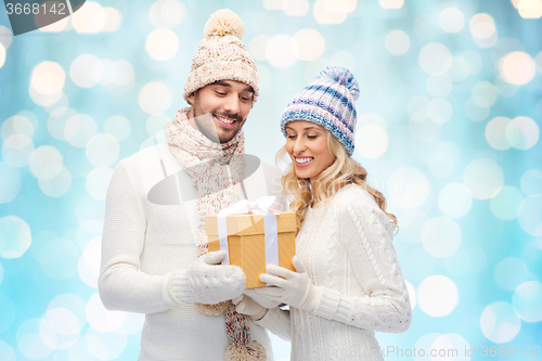 Image of smiling couple in winter clothes with gift box