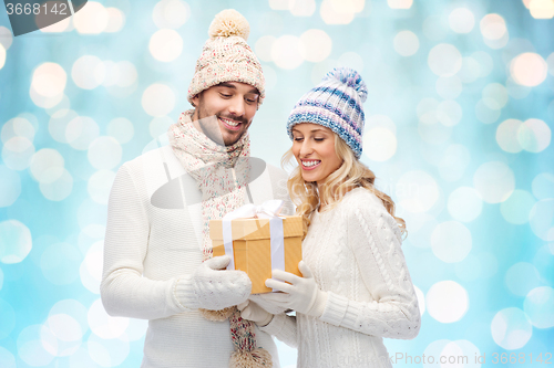 Image of smiling couple in winter clothes with gift box