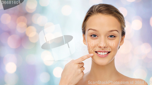 Image of happy young woman pointing finger to her teeth