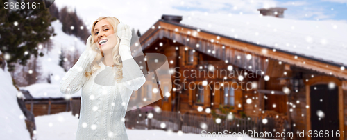 Image of smiling young woman in winter earmuffs outdoors