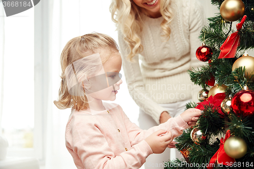 Image of happy family decorating christmas tree at home