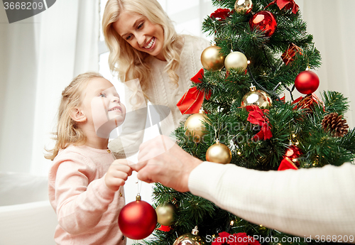 Image of happy family decorating christmas tree at home