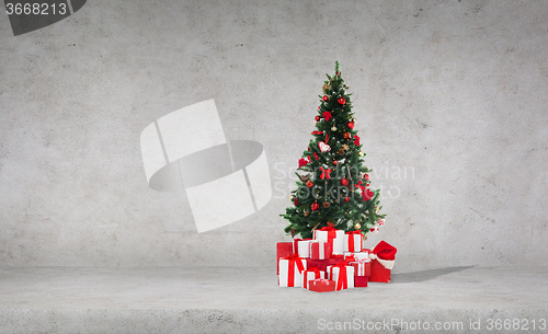 Image of christmas tree with gifts over concrete wall