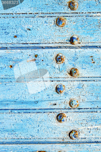 Image of stripped paint in  blue     door and rusty nail