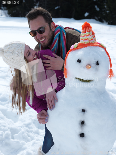 Image of portrait of happy young couple with snowman