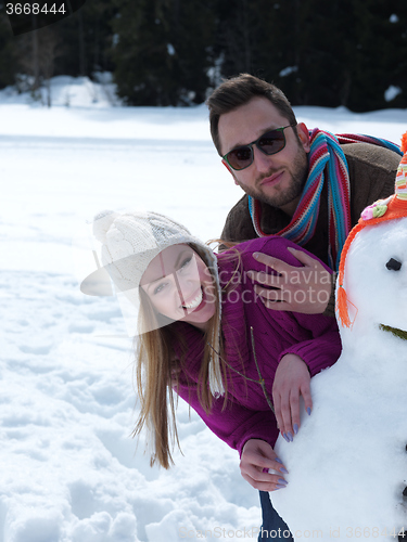 Image of portrait of happy young couple with snowman