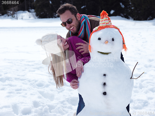 Image of portrait of happy young couple with snowman