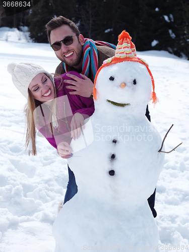 Image of portrait of happy young couple with snowman