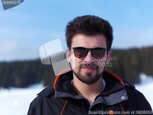 Image of portrait of young man with beard and sunglasses on fresh snow