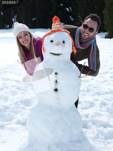 Image of portrait of happy young couple with snowman