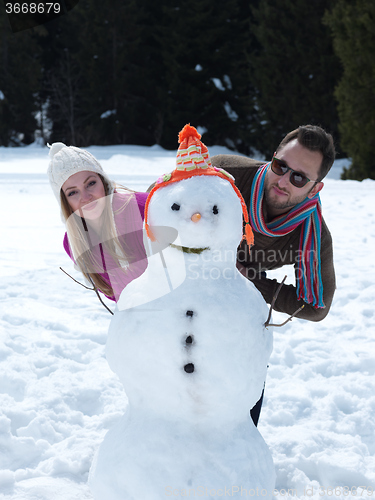 Image of portrait of happy young couple with snowman