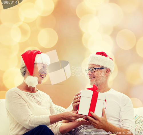 Image of happy senior couple with gift box at home