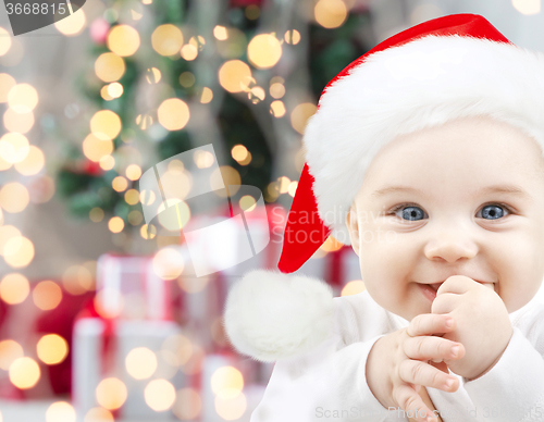 Image of happy baby in santa hat over christmas lights