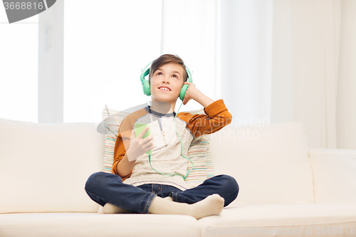 Image of happy boy with smartphone and headphones at home