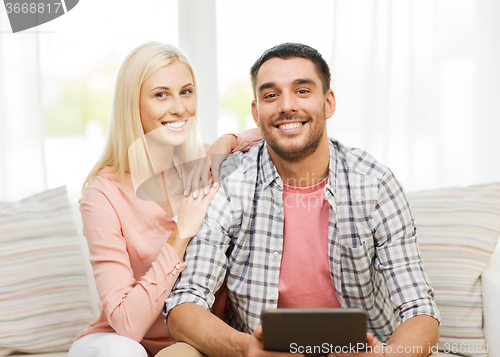 Image of smiling happy couple with tablet pc at home
