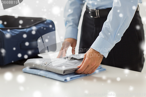 Image of businessman packing clothes into travel bag