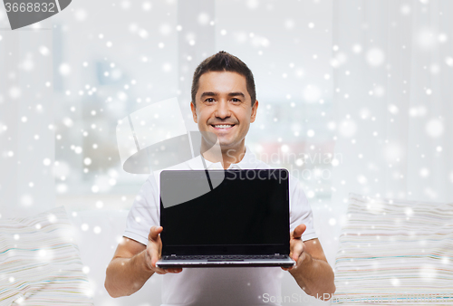 Image of happy man showing laptop blank screen at home