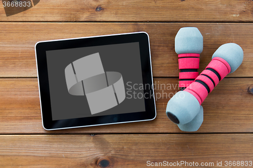 Image of close up of dumbbells and tablet pc on wood