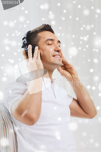 Image of happy man in headphones listening to music at home