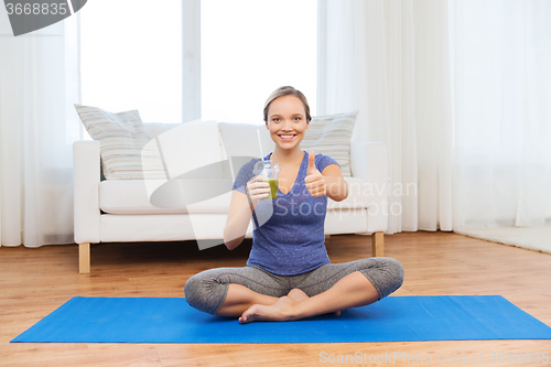 Image of woman with smoothie showing thumbs up at home