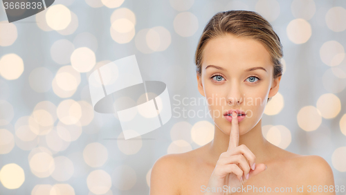 Image of beautiful young woman holding finger on lips