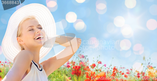 Image of smiling young woman in straw hat on poppy field