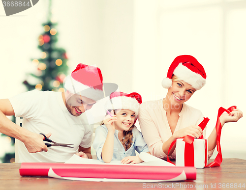 Image of smiling family in santa helper hats with gift box