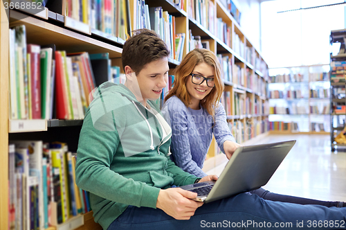 Image of happy students with laptop in library