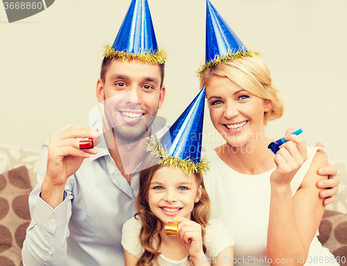 Image of smiling family in blue hats blowing favor horns