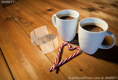 Image of christmas candy canes and cups on wooden table