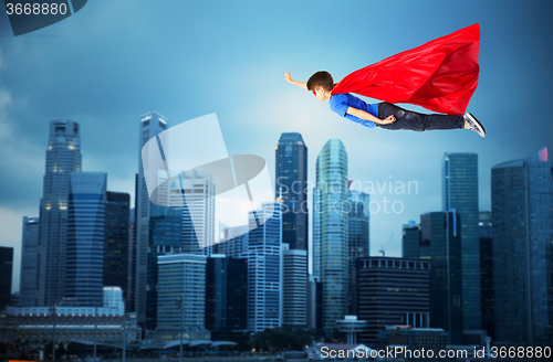 Image of boy in red superhero cape and mask flying on air