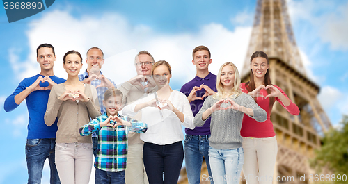 Image of people showing heart hand sign over eiffel tower