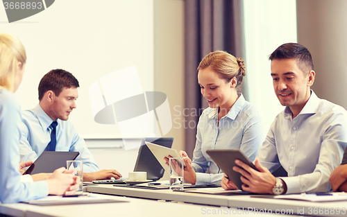 Image of smiling business people with tablet pc in office