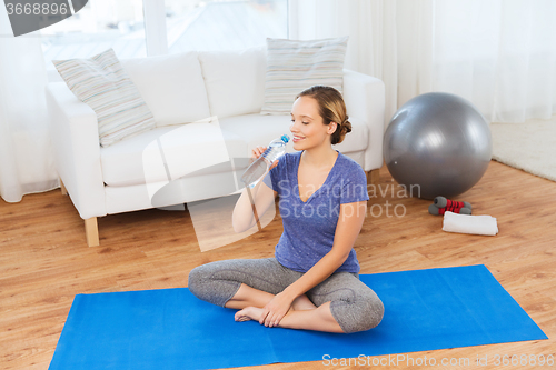 Image of happy woman with water bottle exercising at home