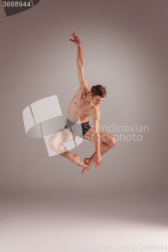 Image of The young attractive modern ballet dancer jumping on gray background